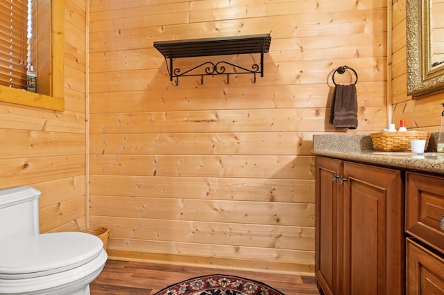 bathroom featuring wood walls, vanity, toilet, and hardwood / wood-style floors