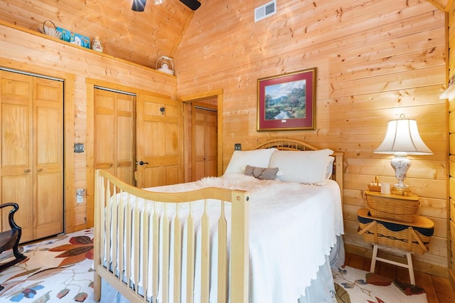 bedroom featuring lofted ceiling, multiple closets, and wooden walls