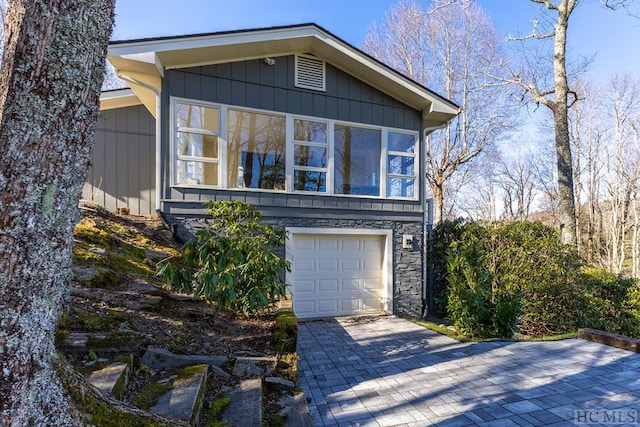 view of front of property with decorative driveway, board and batten siding, and stone siding