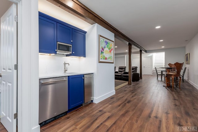 bar with appliances with stainless steel finishes, sink, blue cabinets, and dark hardwood / wood-style floors