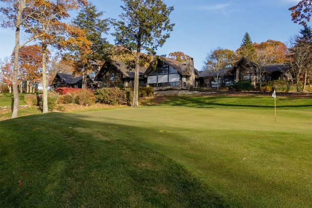 view of community featuring a putting area, a lawn, and golf course view