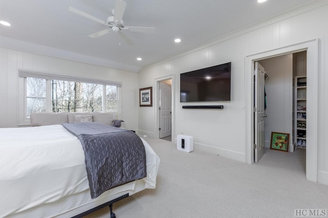 carpeted bedroom with a spacious closet, crown molding, baseboards, recessed lighting, and a ceiling fan