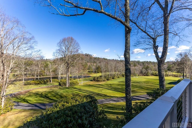 view of community featuring a view of trees, a yard, and view of golf course