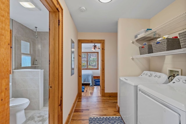 laundry area with light wood-style flooring, a ceiling fan, separate washer and dryer, laundry area, and baseboards