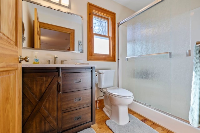 bathroom with wood finished floors, a stall shower, vanity, and toilet