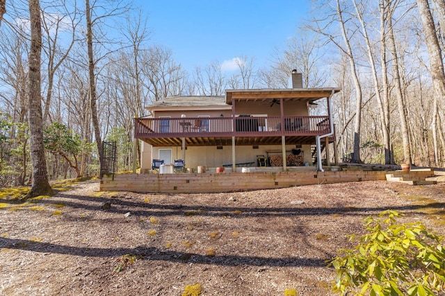 back of house with a chimney and a wooden deck