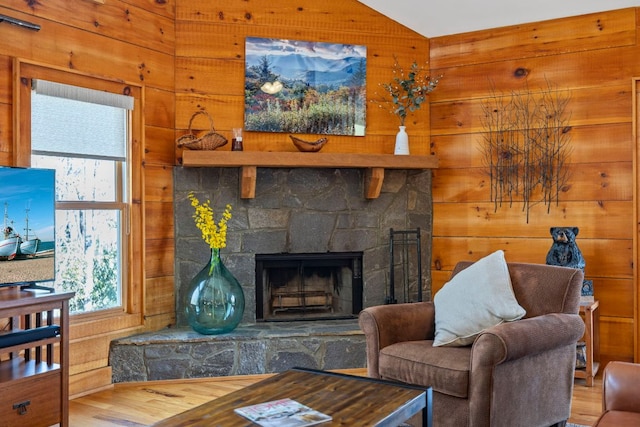 living room with vaulted ceiling, a fireplace, and wooden walls