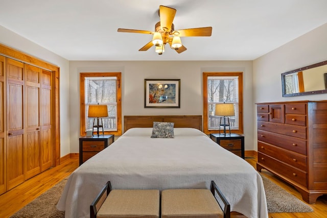 bedroom with light wood finished floors, baseboards, a ceiling fan, and a closet