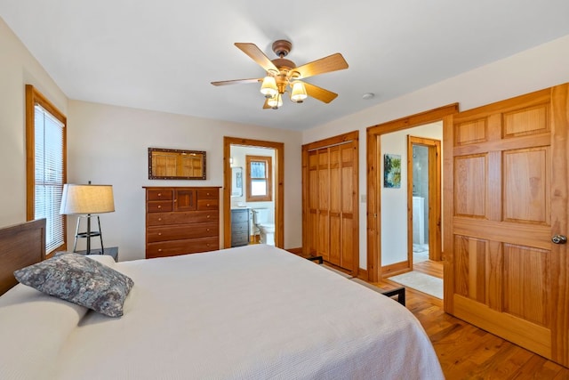 bedroom featuring a closet, a ceiling fan, connected bathroom, wood finished floors, and baseboards