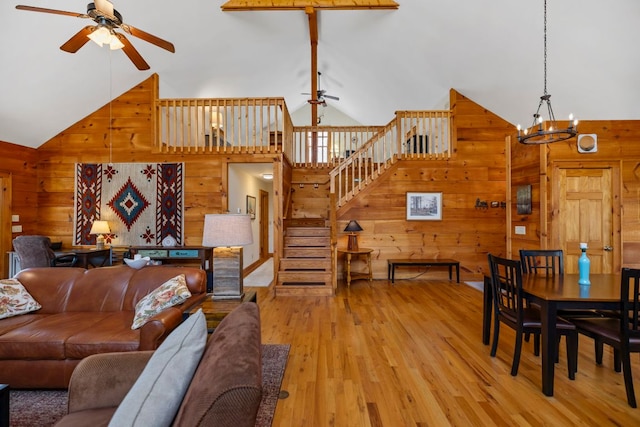 living area with stairs, wooden walls, and ceiling fan with notable chandelier