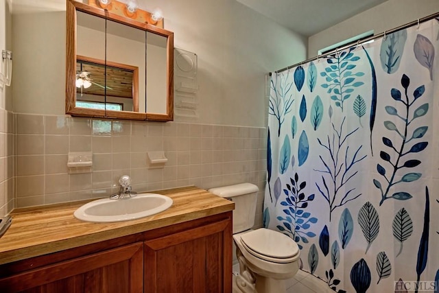 bathroom featuring walk in shower, vanity, toilet, and tile walls