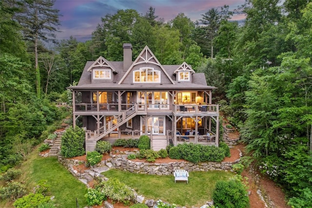 421 Easter Ln, Cullowhee, NC 28723 - back of house at dusk featuring stairs, a chimney, a patio area, and a view of trees