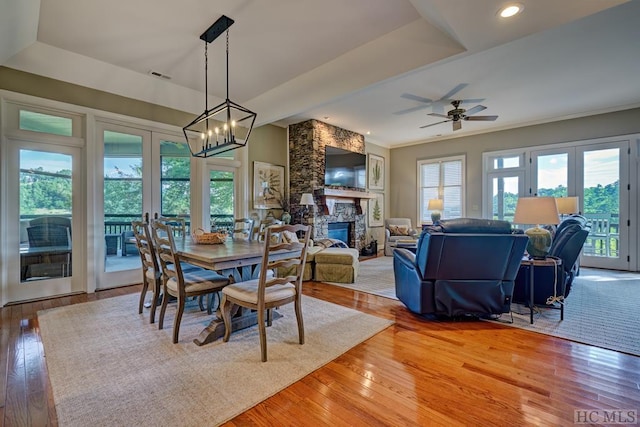 dining area featuring hardwood / wood-style flooring, a tray ceiling, french doors, and a fireplace