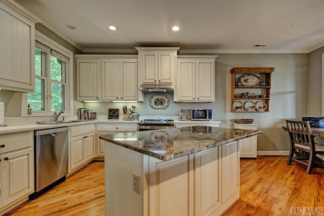 kitchen featuring appliances with stainless steel finishes, a kitchen island, ornamental molding, and dark stone counters