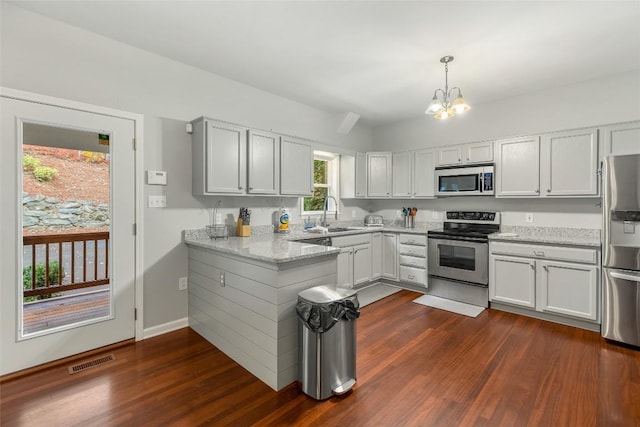 110 Kestrel Ct, Sapphire, NC 28774 - kitchen featuring appliances with stainless steel finishes, dark wood-type flooring, a peninsula, a chandelier, and hanging light fixtures