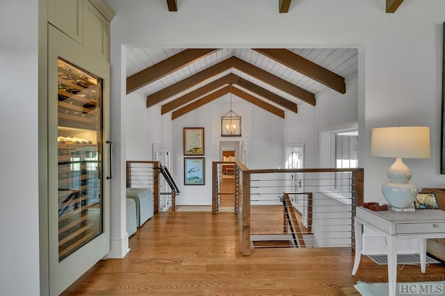 hall with beam ceiling, a chandelier, high vaulted ceiling, and light hardwood / wood-style flooring