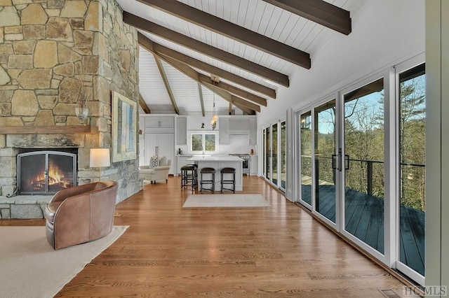 interior space featuring beamed ceiling, a fireplace, high vaulted ceiling, and light hardwood / wood-style flooring