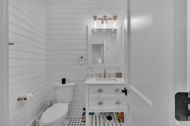 bathroom with vanity, toilet, and wood walls