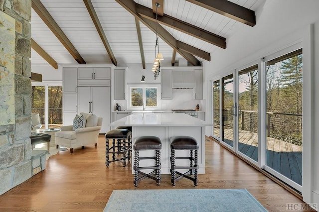 kitchen featuring white cabinetry, light hardwood / wood-style floors, paneled fridge, and beamed ceiling