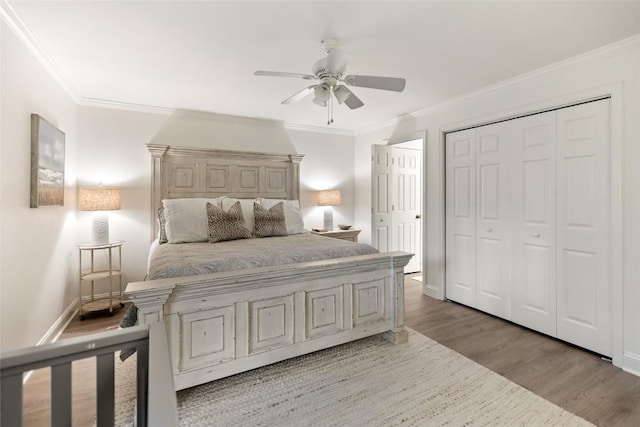 bedroom featuring wood finished floors, a closet, baseboards, ceiling fan, and ornamental molding