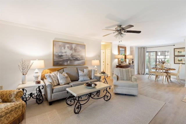 living room featuring wood finished floors, a ceiling fan, and ornamental molding