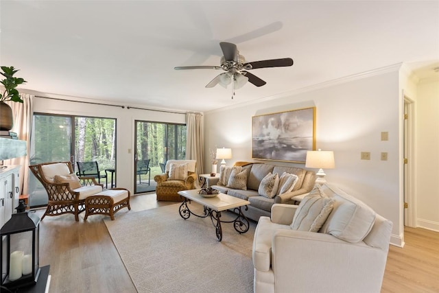 living room featuring crown molding, ceiling fan, baseboards, and light wood-type flooring