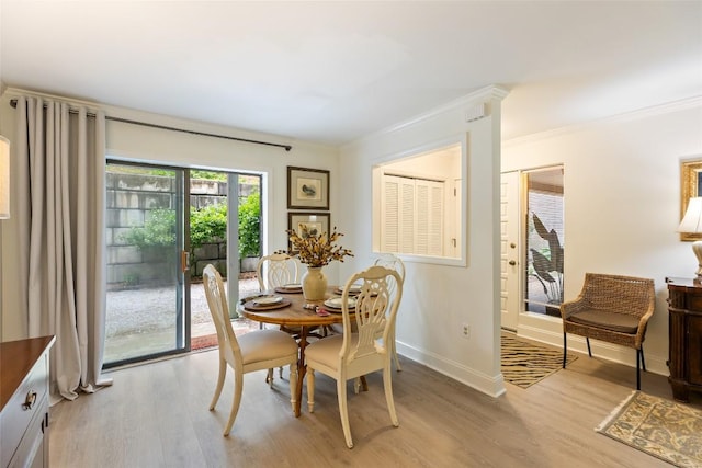 dining area with light wood finished floors, baseboards, and ornamental molding