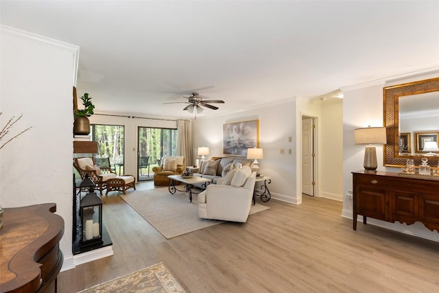 living area with light wood-style floors, baseboards, a ceiling fan, and ornamental molding