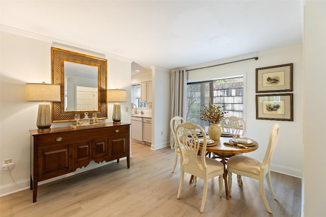 dining room featuring baseboards, light wood-style floors, and crown molding