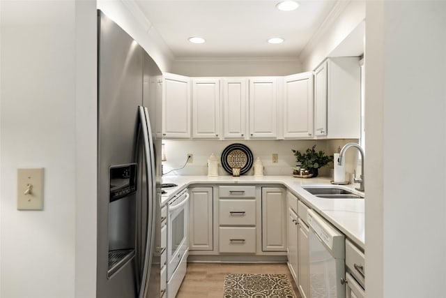 kitchen featuring a sink, light wood-type flooring, white appliances, light countertops, and recessed lighting