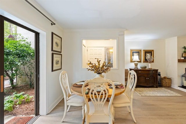 dining room with crown molding, baseboards, and light wood-type flooring