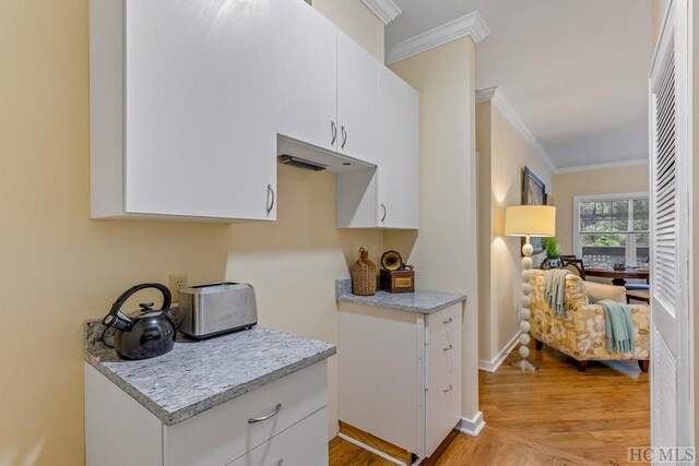 kitchen featuring white cabinetry, light stone counters, and ornamental molding