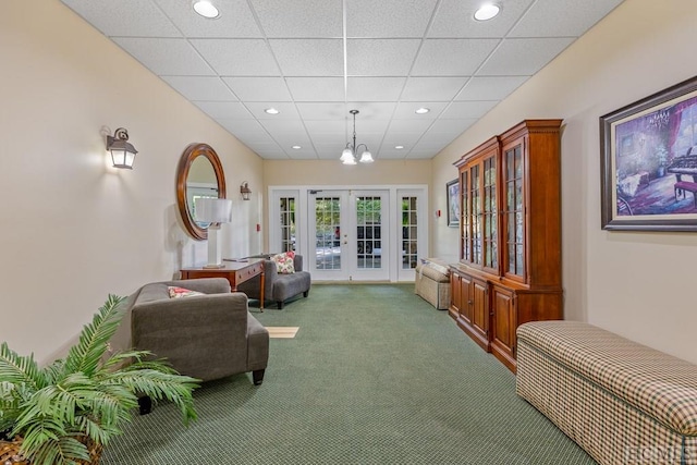 sitting room featuring a drop ceiling, carpet, and french doors