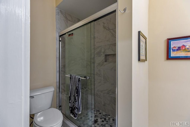 bathroom with a shower with shower door and toilet