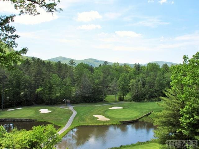 view of community featuring view of golf course, a water view, and a yard