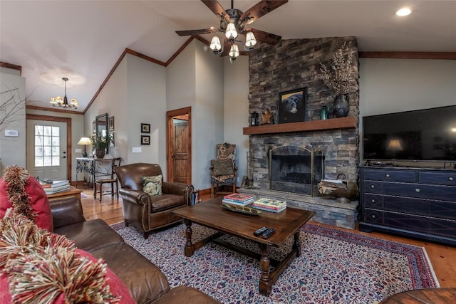 living area with ceiling fan with notable chandelier, a fireplace, wood finished floors, vaulted ceiling, and ornamental molding