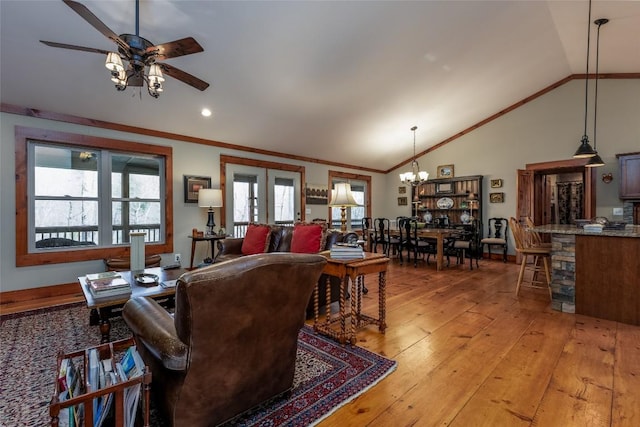 living area featuring lofted ceiling, light wood-style floors, ceiling fan with notable chandelier, and crown molding