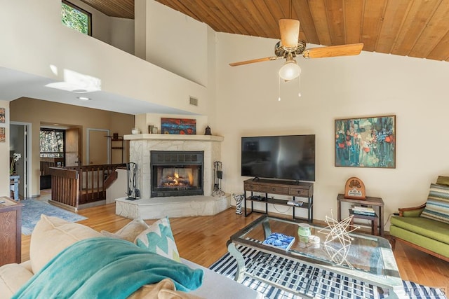 living room featuring high vaulted ceiling, wooden ceiling, light wood-type flooring, ceiling fan, and a fireplace