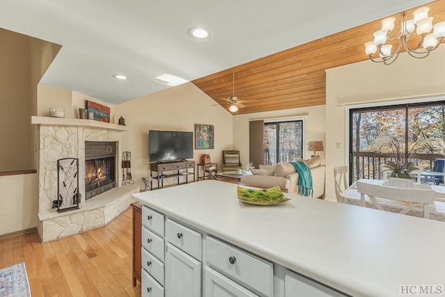 kitchen with lofted ceiling, wood ceiling, light hardwood / wood-style flooring, a fireplace, and ceiling fan with notable chandelier