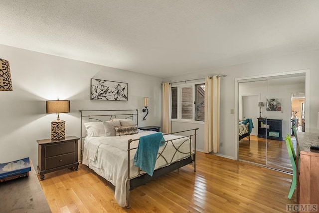 bedroom with a textured ceiling, a closet, and light wood-type flooring