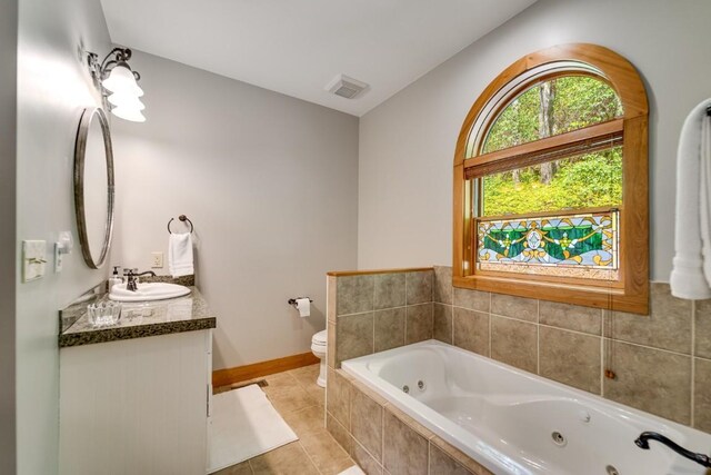 full bath featuring a tub with jets, tile patterned floors, toilet, baseboards, and vanity
