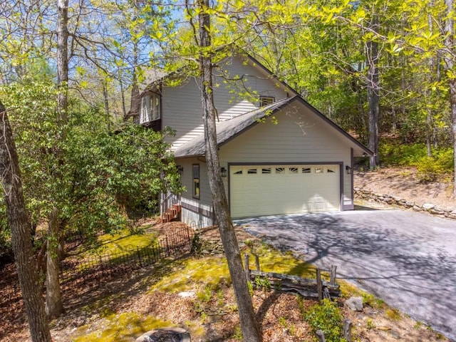 view of side of home featuring driveway, fence, and a garage