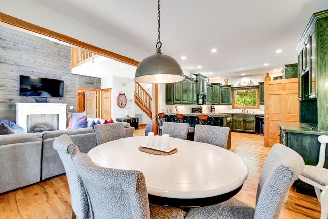 dining space with stairway, light wood-style floors, wooden walls, a fireplace, and recessed lighting
