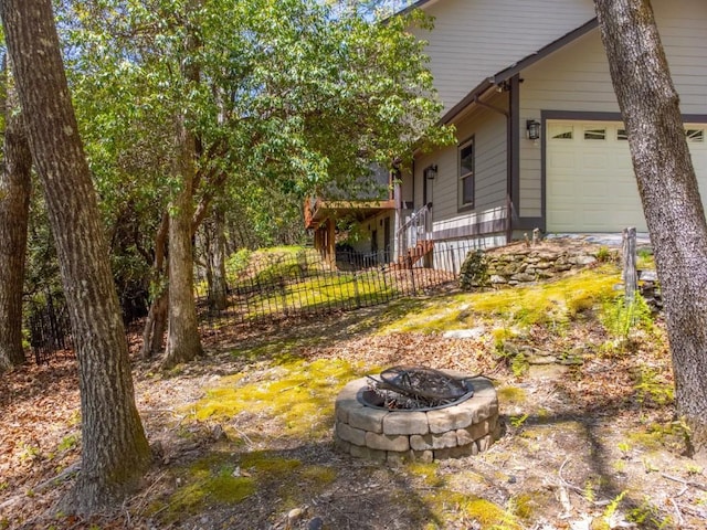 view of side of home with a fire pit, fence, and an attached garage