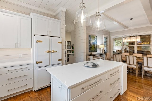 kitchen with dark wood-type flooring, decorative light fixtures, paneled built in fridge, a kitchen island, and white cabinets