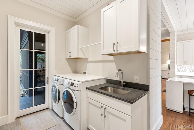 laundry area with sink, crown molding, light hardwood / wood-style flooring, washing machine and dryer, and cabinets