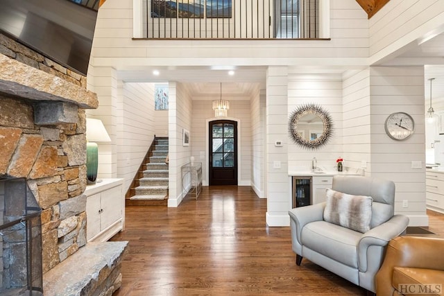 entrance foyer featuring a towering ceiling, dark hardwood / wood-style floors, beverage cooler, and wood walls