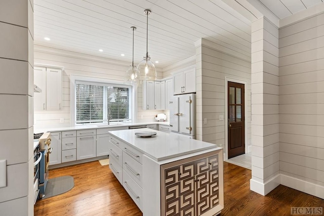 kitchen with pendant lighting, hardwood / wood-style floors, a center island, white cabinets, and white fridge