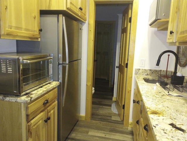 kitchen featuring dark hardwood / wood-style floors, light stone countertops, and sink