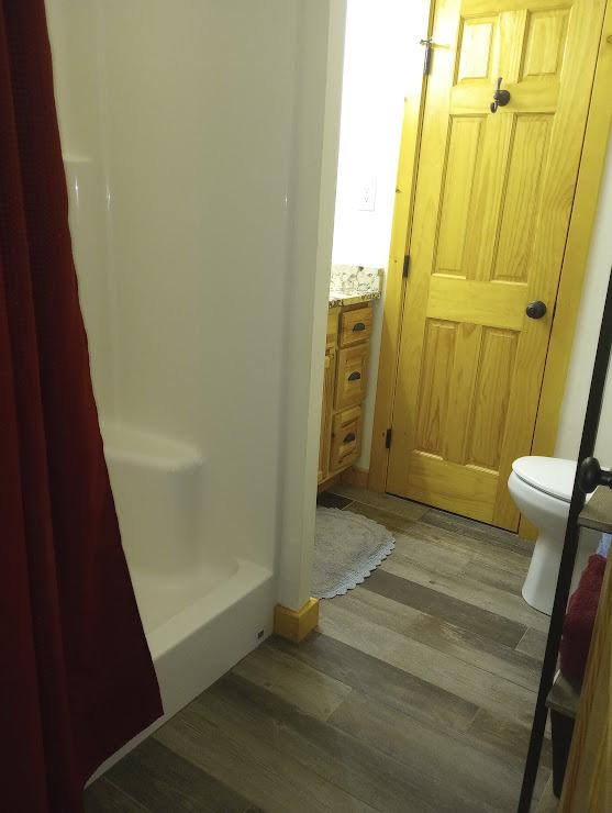 bathroom featuring hardwood / wood-style flooring, toilet, and walk in shower